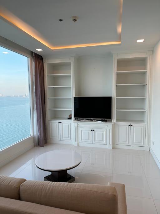 Modern living room with sea view, built-in shelves, and large windows