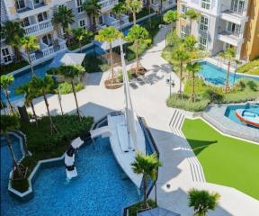 Aerial view of a luxurious outdoor pool area with surrounding palm trees and residential buildings