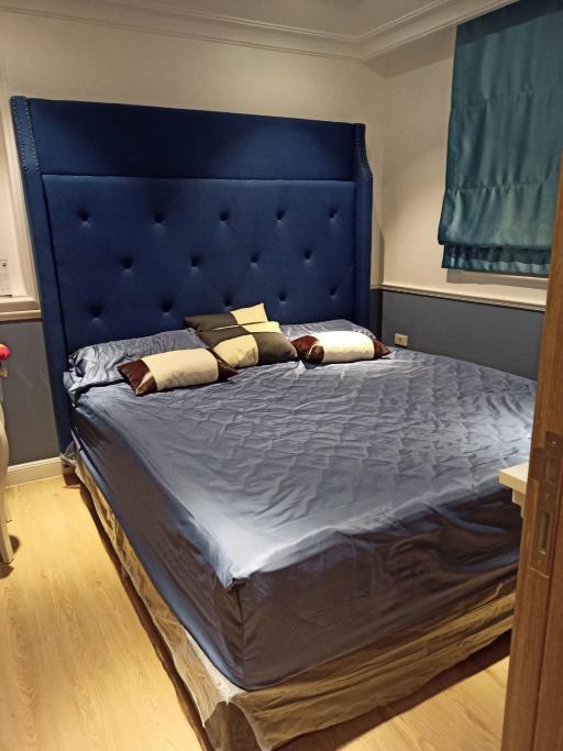 Elegant bedroom with large blue upholstered headboard and hardwood floors