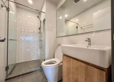 Modern bathroom with glass shower enclosure and wooden cabinet