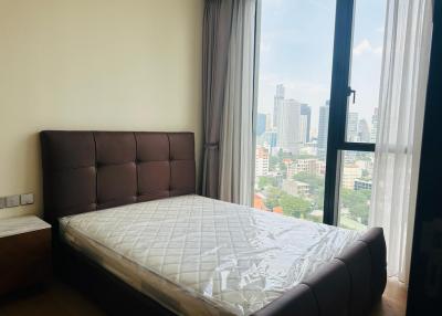 Spacious bedroom with a large window overlooking the city