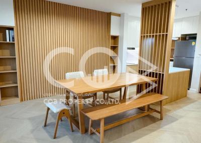 Modern dining area adjacent to kitchen with wooden table, chairs, and decorative slatted wood panel