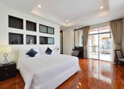 Spacious bedroom with hardwood floors, large windows, and modern decor
