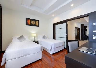 Spacious bedroom with two beds, artwork, and modern amenities.