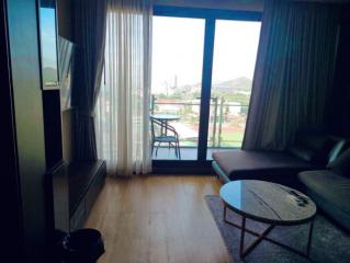 Cozy living room with a modern sofa, TV, and a view through the balcony door