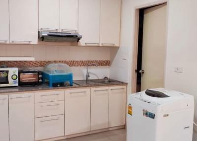 Modern kitchen with white cabinets, appliances, and a washing machine