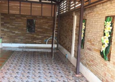 Spacious covered patio area with ceramic tile flooring and brick walls