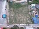 Aerial view of a spacious vacant land plot with nearby housing and vegetation, suitable for development