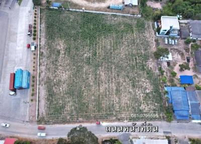Aerial view of a spacious vacant land plot with nearby housing and vegetation, suitable for development
