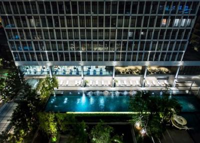 Night view of a modern building exterior with illuminated windows and a pool