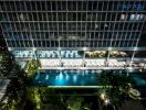 Night view of a modern building exterior with illuminated windows and a pool