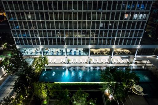 Night view of a modern building exterior with illuminated windows and a pool