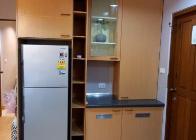 Compact kitchen area with refrigerator and wooden cabinets
