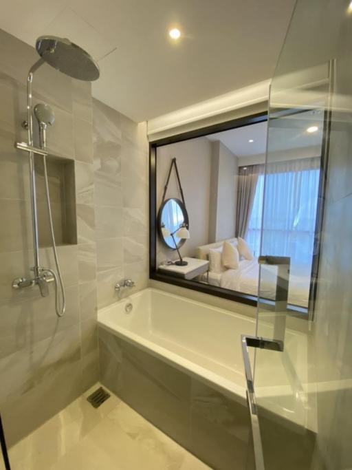 Modern bathroom with glass shower partition and view into the bedroom