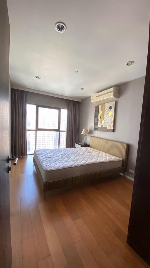 Spacious and well-lit bedroom interior with large bed and city view
