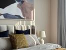 Elegant bedroom interior with a plush headboard, decorative cushions, and abstract wall art