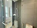 Modern bathroom with glass shower enclosure and grey tiles