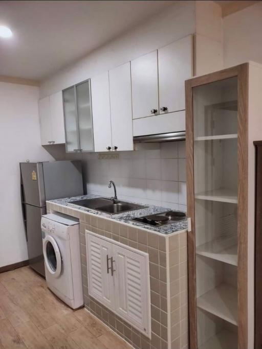 Compact kitchen with white cabinets, washing machine, and built-in sink