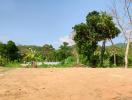 empty plot of land with greenery in the background under a clear blue sky