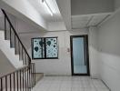 Interior view of a building hallway with tiled flooring and staircase