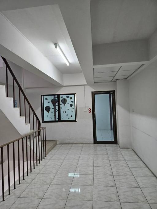 Interior view of a building hallway with tiled flooring and staircase