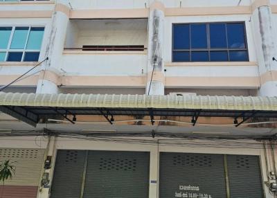 Three-story commercial-residential building with gray roller shutters