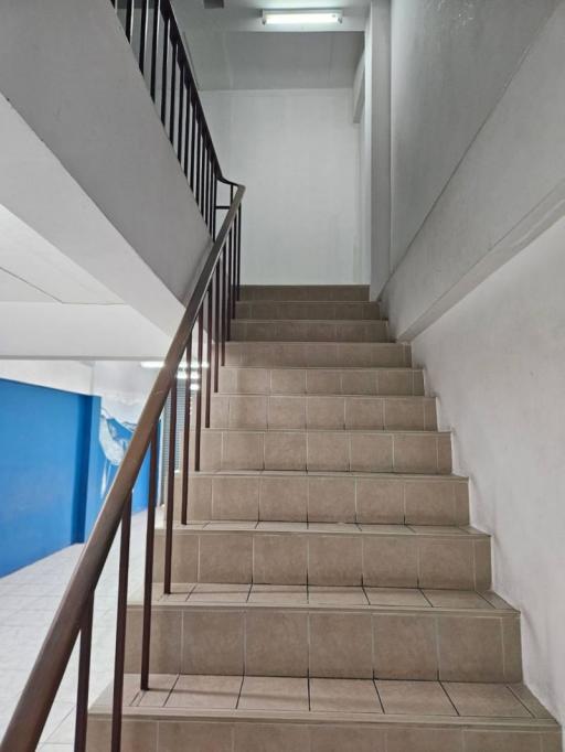 Tile-floored staircase with metal railing inside a residential building