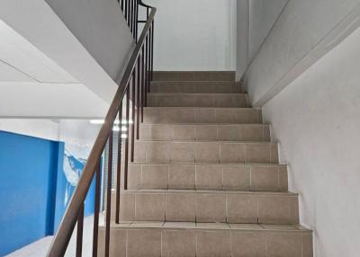 Tile-floored staircase with metal railing inside a residential building