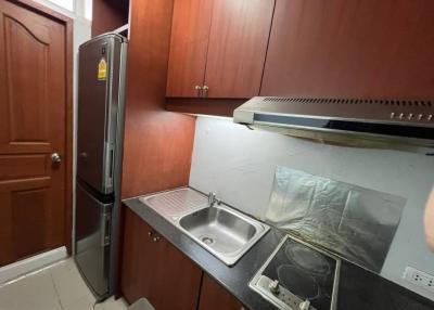 Compact kitchen with wooden cabinets, stainless steel sink, and modern appliances