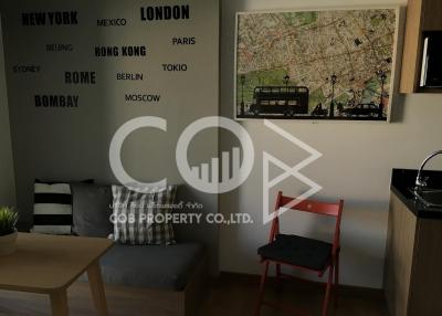 Modern living room with a sofa and a wooden coffee table, decorated with a world cities wall art and a framed map
