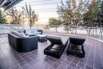 Spacious balcony with modern outdoor furniture and a view of the sunset