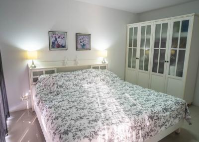 Cozy well-lit bedroom with a large floral-patterned bed and stylish wardrobe