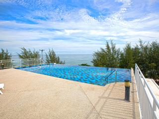 Outdoor infinity pool with ocean view and sunny sky