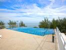 Outdoor infinity pool with ocean view and sunny sky