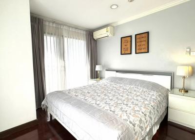 Bright and elegantly furnished bedroom with queen-sized bed and wood flooring