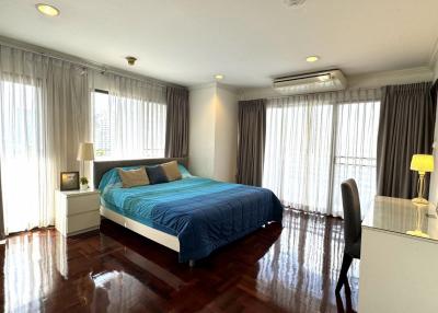 Spacious bedroom with large windows, hardwood floors, and modern furnishings