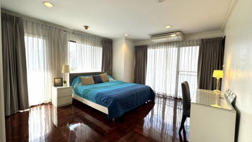 Spacious bedroom with large windows, hardwood floors, and modern furnishings