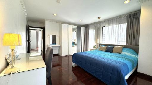 Spacious bedroom with modern design, hardwood flooring, and large windows