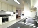 Spacious modern kitchen with stainless steel sink, granite countertops, and built-in appliances