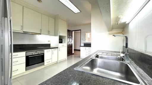 Spacious modern kitchen with stainless steel sink, granite countertops, and built-in appliances