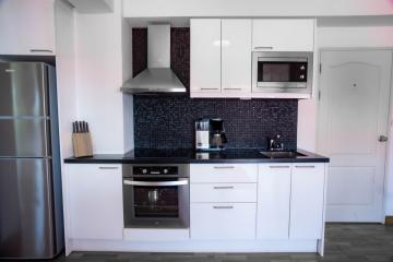 Modern kitchen with stainless steel appliances and black backsplash