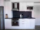 Modern kitchen with stainless steel appliances and black backsplash