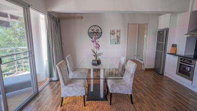 Modern living space with dining area and open kitchen, featuring hardwood floors and natural light