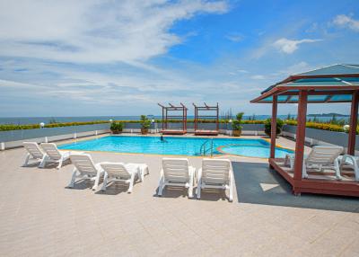 Luxurious outdoor swimming pool with lounging chairs and pavilion with ocean view