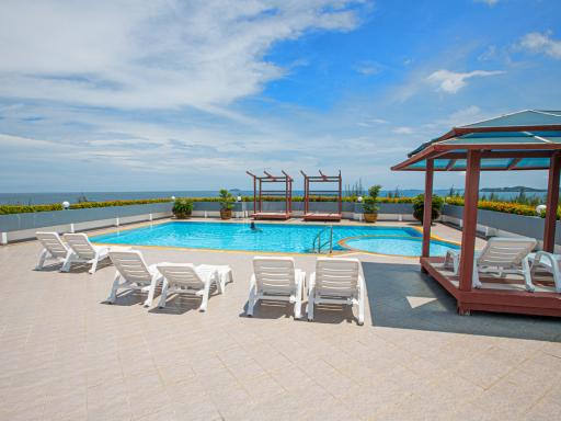 Luxurious outdoor swimming pool with lounging chairs and pavilion with ocean view