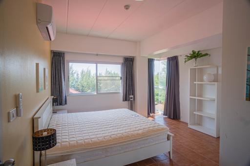 Bright and airy bedroom with a large window, white bedding, and minimalist decor