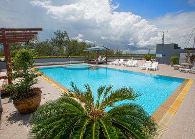 Spacious outdoor swimming pool with lounge chairs and beautiful sky view