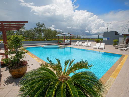 Spacious outdoor swimming pool with lounge chairs and beautiful sky view