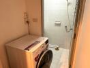 Compact utility room with a washing machine and a white-tiled wall