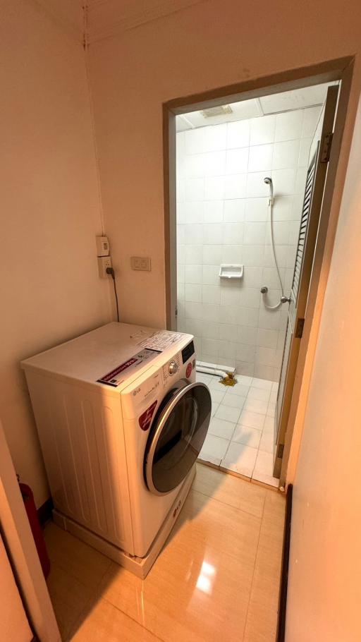 Compact utility room with a washing machine and a white-tiled wall